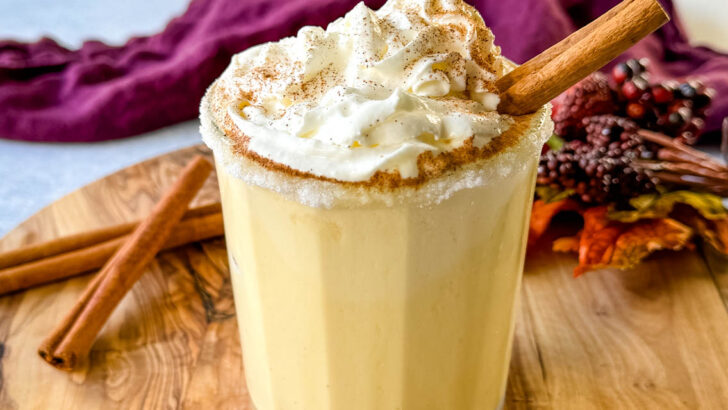 spiked eggnog with liquor, cinnamon, and whipped cream on a flat surface