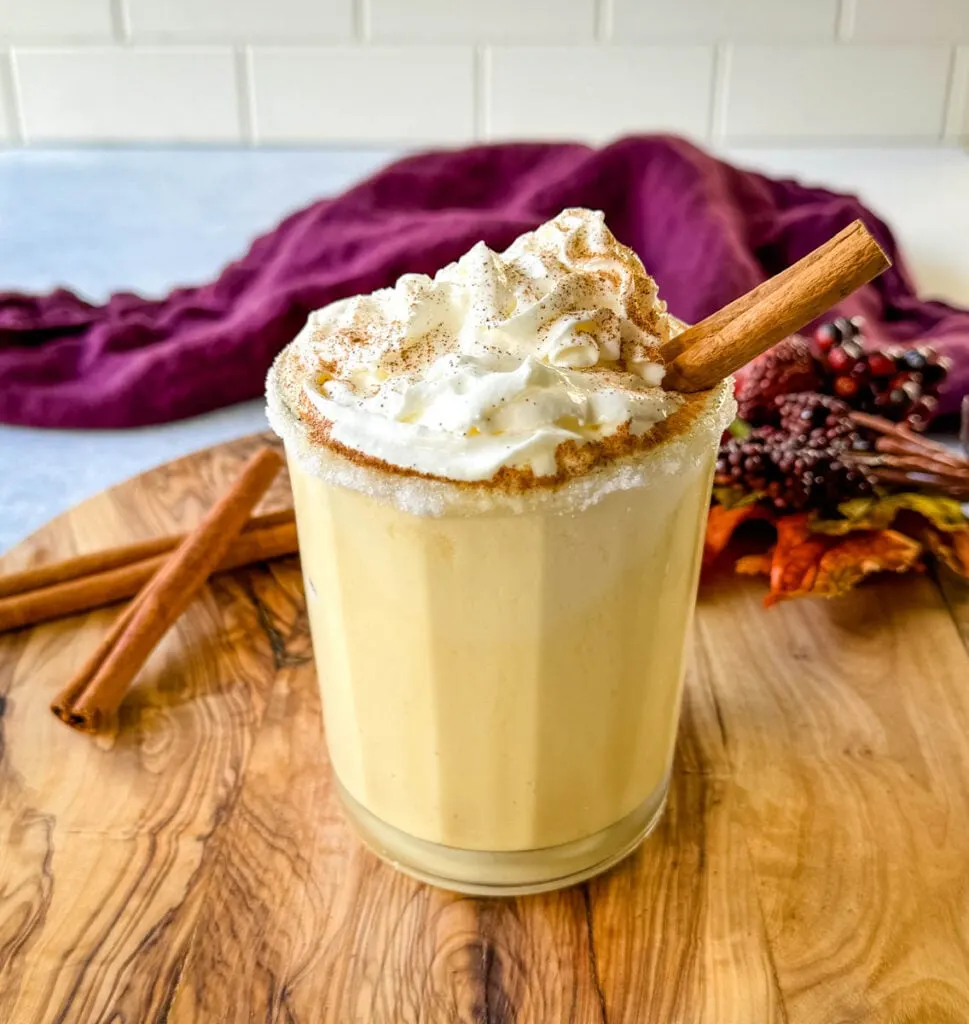 spiked eggnog with liquor, cinnamon, and whipped cream on a flat surface