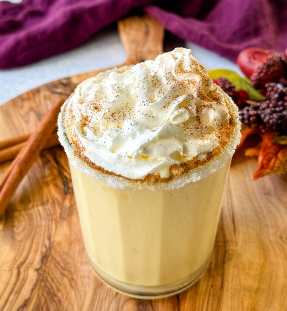 spiked eggnog with liquor, cinnamon, and whipped cream on a flat surface