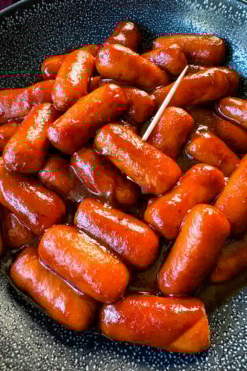 little smokies and BBQ sauce in a black bowl with a toothpick