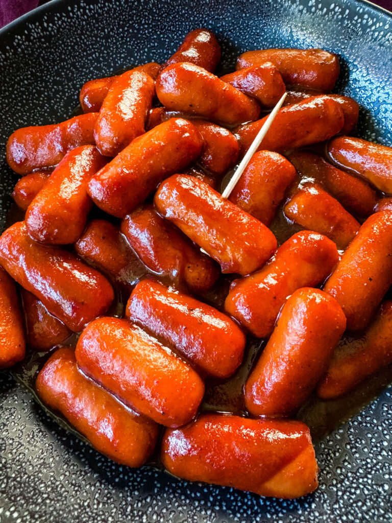 little smokies and BBQ sauce in a black bowl with a toothpick