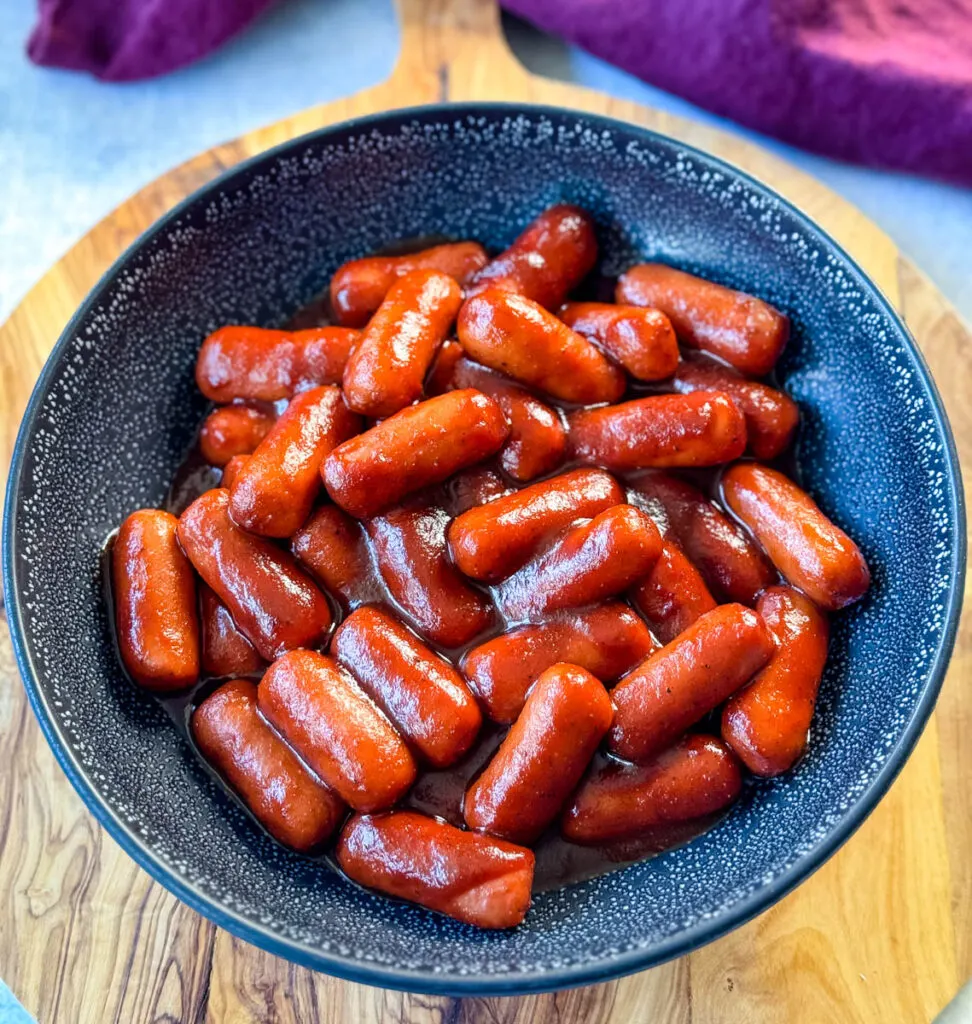 little smokies and BBQ sauce in a black bowl with a toothpick