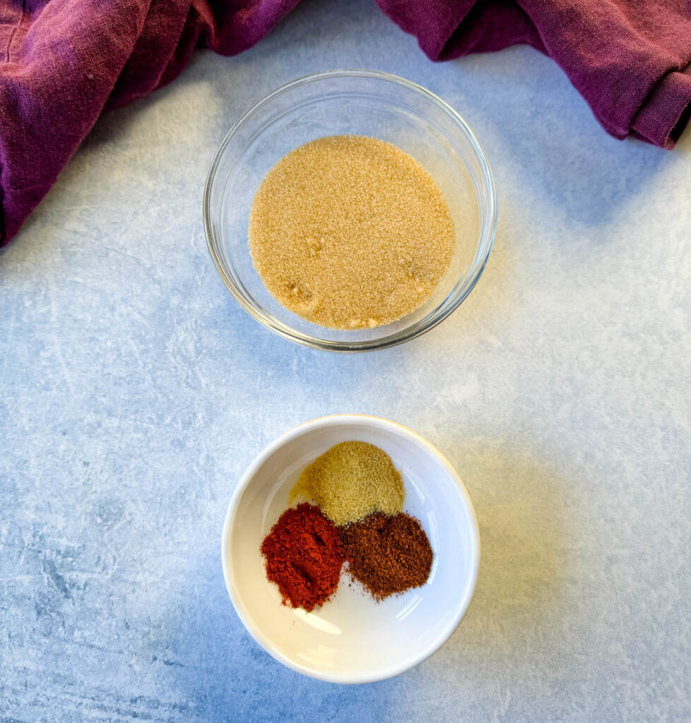 brown sugar, chili powder, garlic powder, and smoked paprika in separate white bowls
