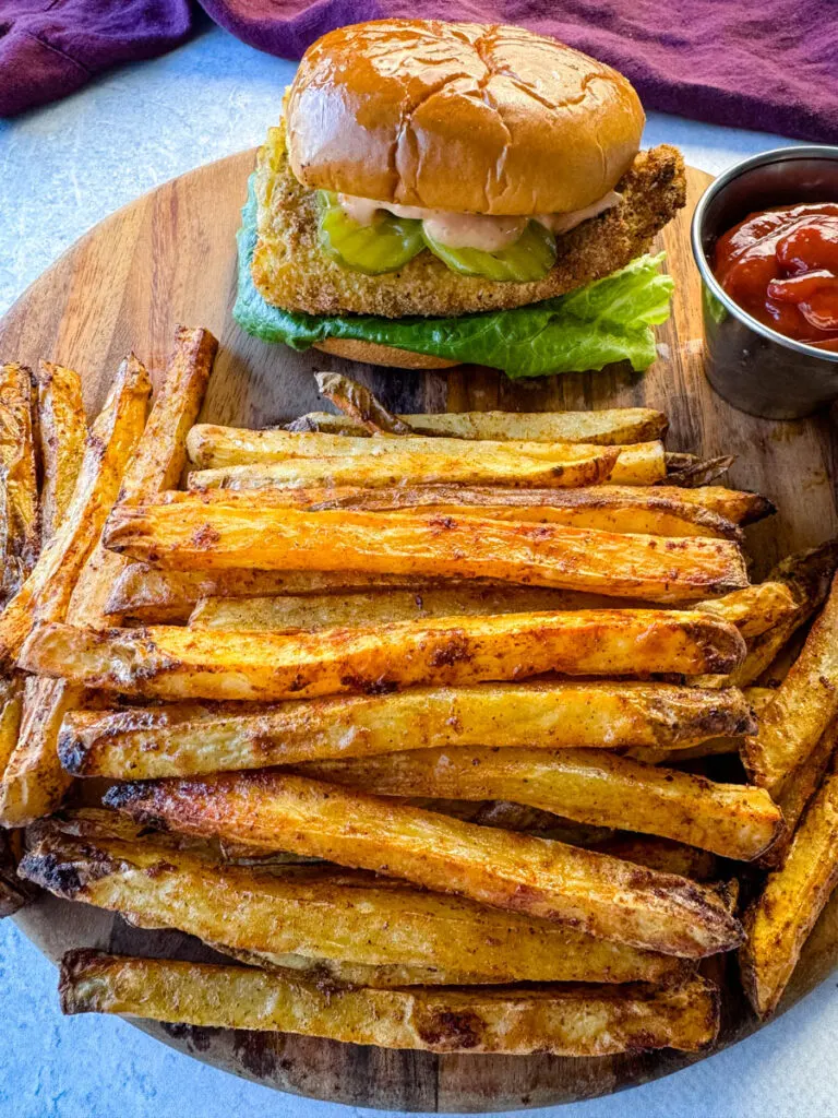 Cajun fries and a fish sandwich on a platter with ketchup