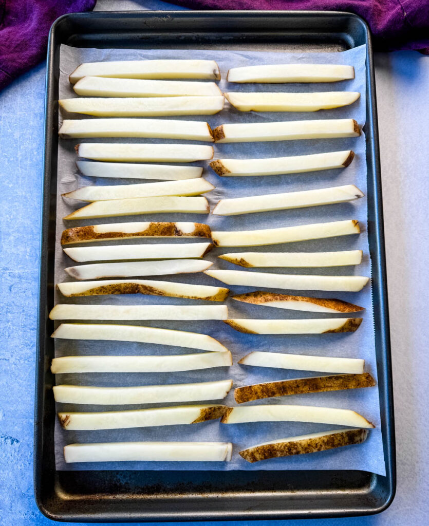 sliced potatoes on a sheet pan with parchment paper