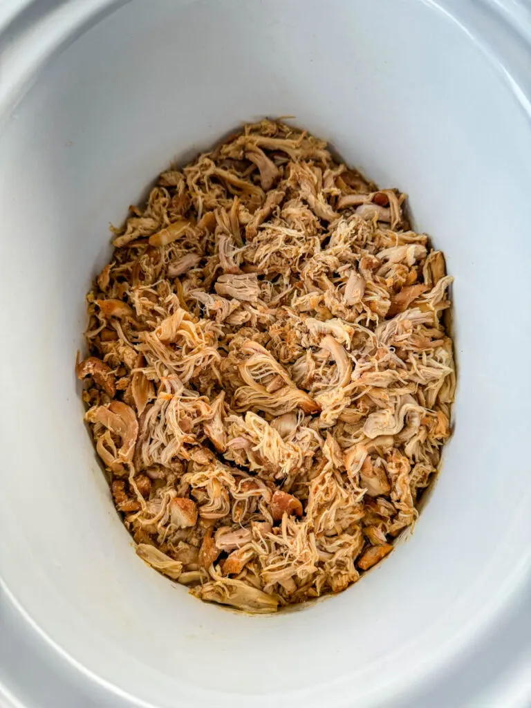 pulled chicken in a white Crockpot slow cooker