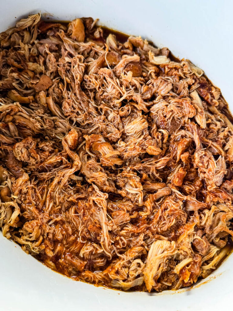 pulled chicken and BBQ sauce in a white Crockpot slow cooker