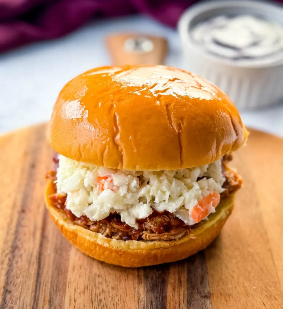 smoked pulled chicken sandwich with BBQ sauce and coleslaw on a plate