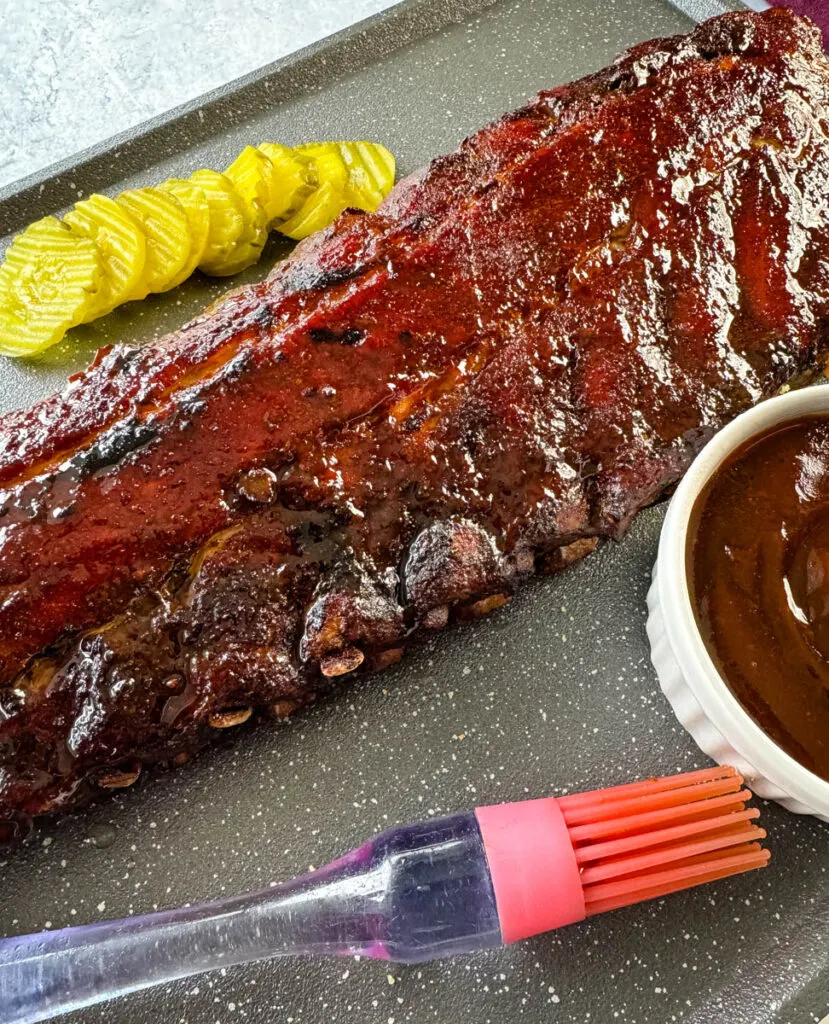 cooked ribs with BBQ sauce on a plate with pickles