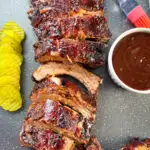 oven baked ribs on a sheet pan with BBQ sauce and pickles