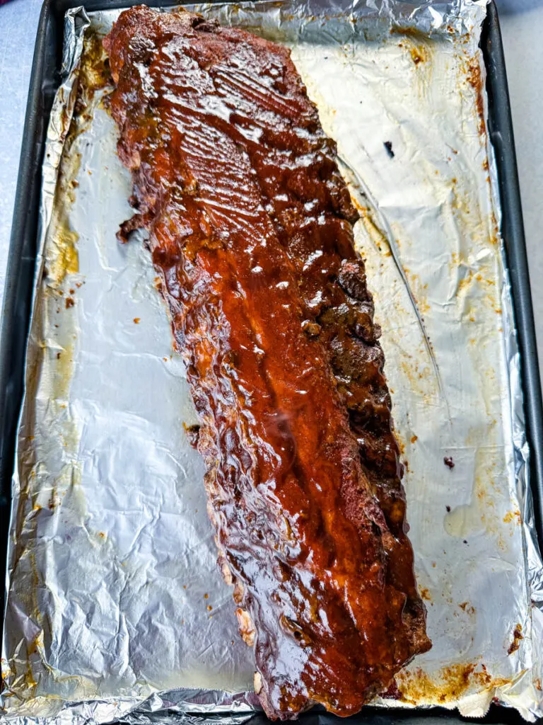 oven baked ribs on foil with BBQ sauce
