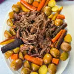cooked beef pot roast, carrots, and potatoes on a white plate