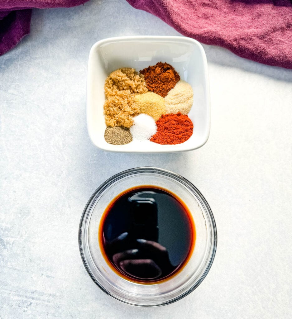 BBQ dry rub spices in a white bowl and soy sauce in a glass bowl