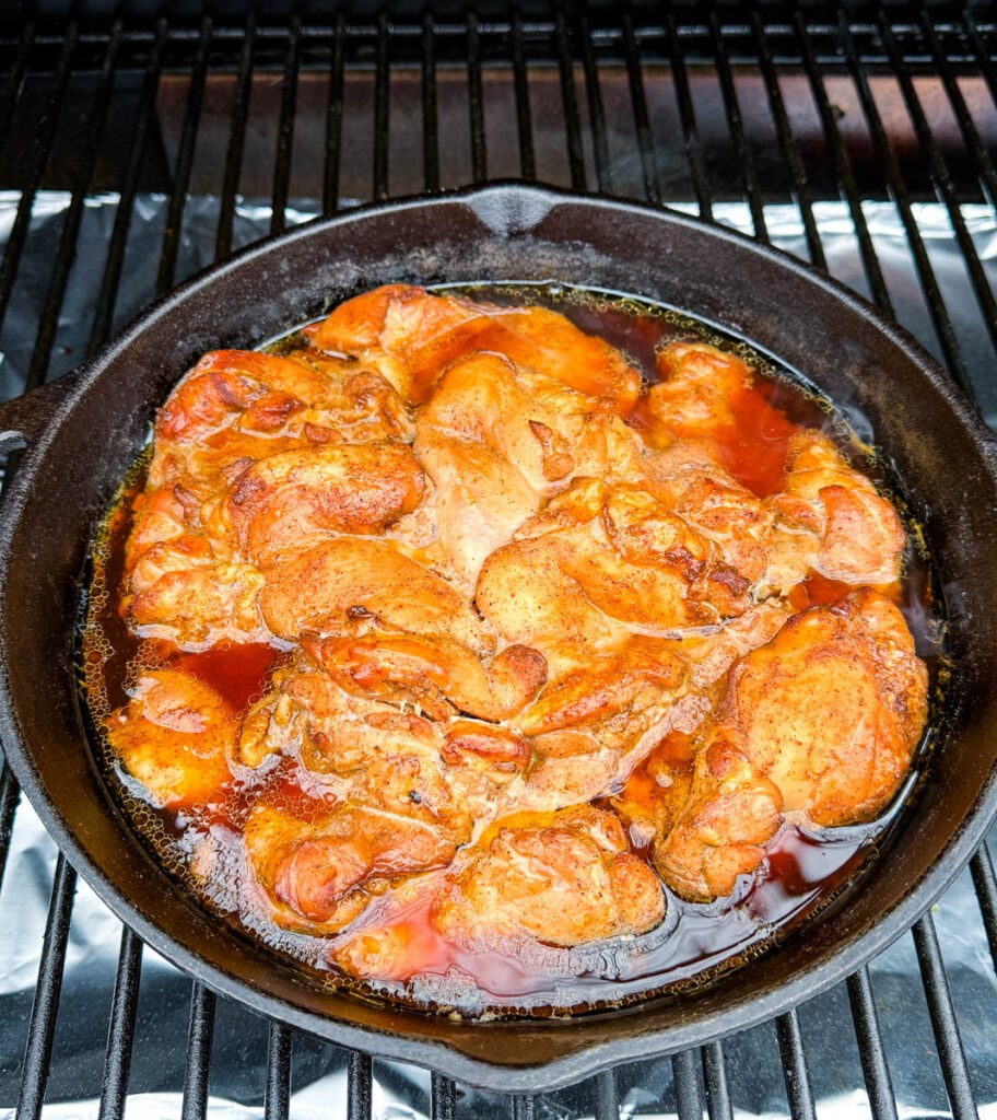 smoked pulled chicken thighs in a cast iron skillet on a Traeger pellet grill smoker