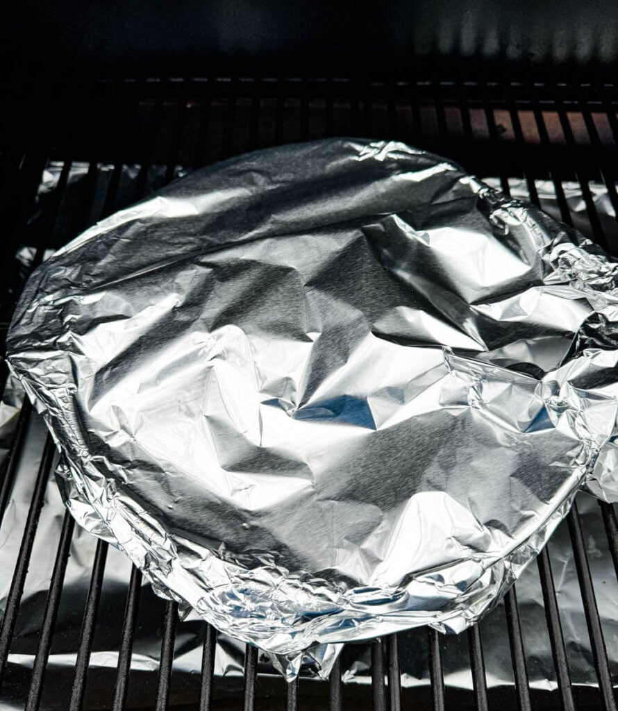 chicken thighs wrapped in foil on a Traeger pellet grill smoker