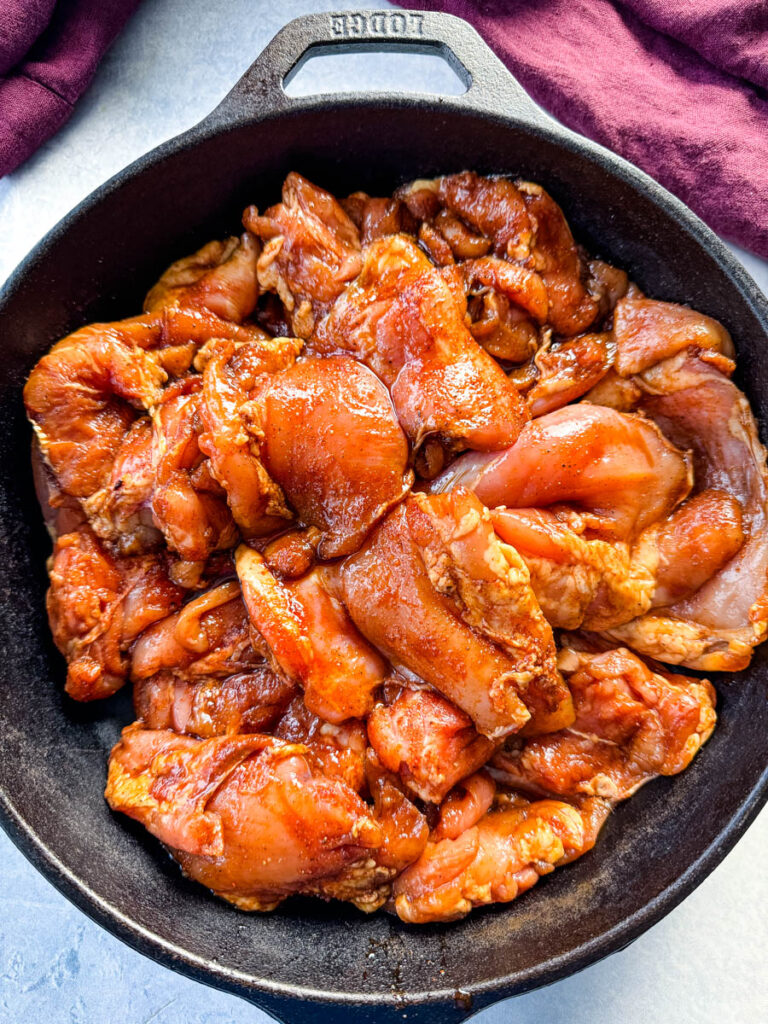 raw seasoned and marinated chicken thighs in a cast iron skillet