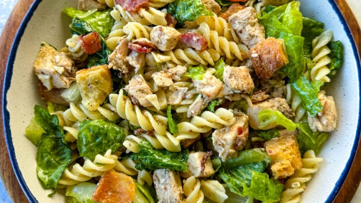 Chicken Caesar Pasta Salad with bacon and croutons in a white bowl