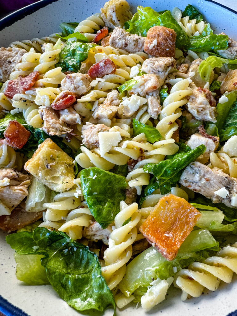 Chicken Caesar Pasta Salad with bacon and croutons in a white bowl