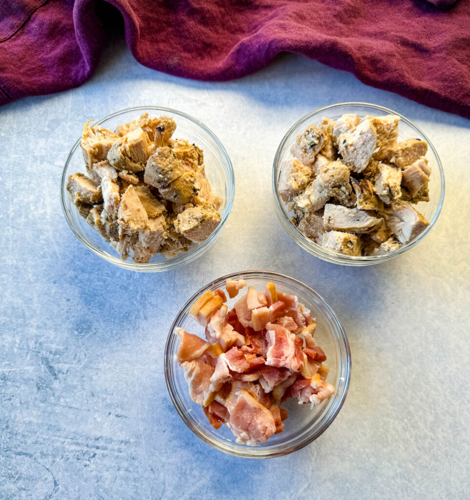cooked chicken and bacon in separate glass bowls
