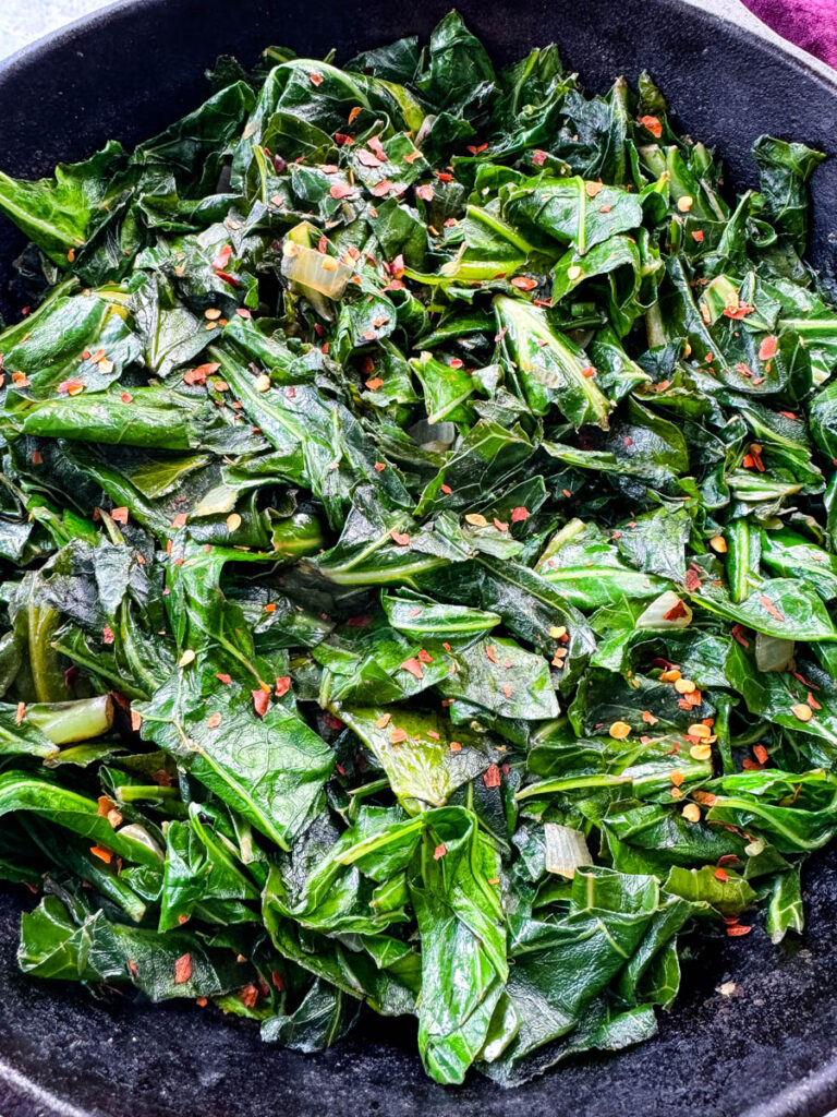 sauteed collard greens with crushed red pepper in a cast iron skillet