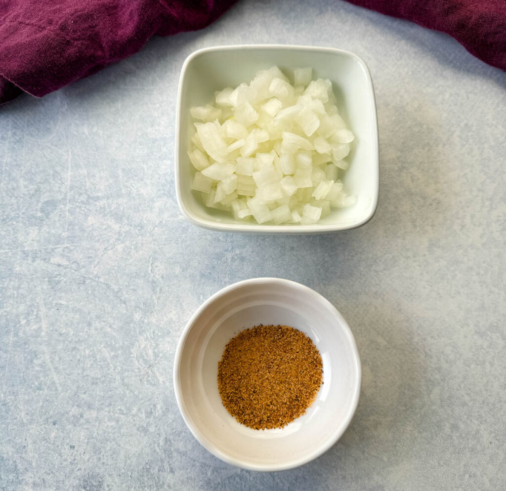 chopped white onions and Creole Seasoning in separate white bowls