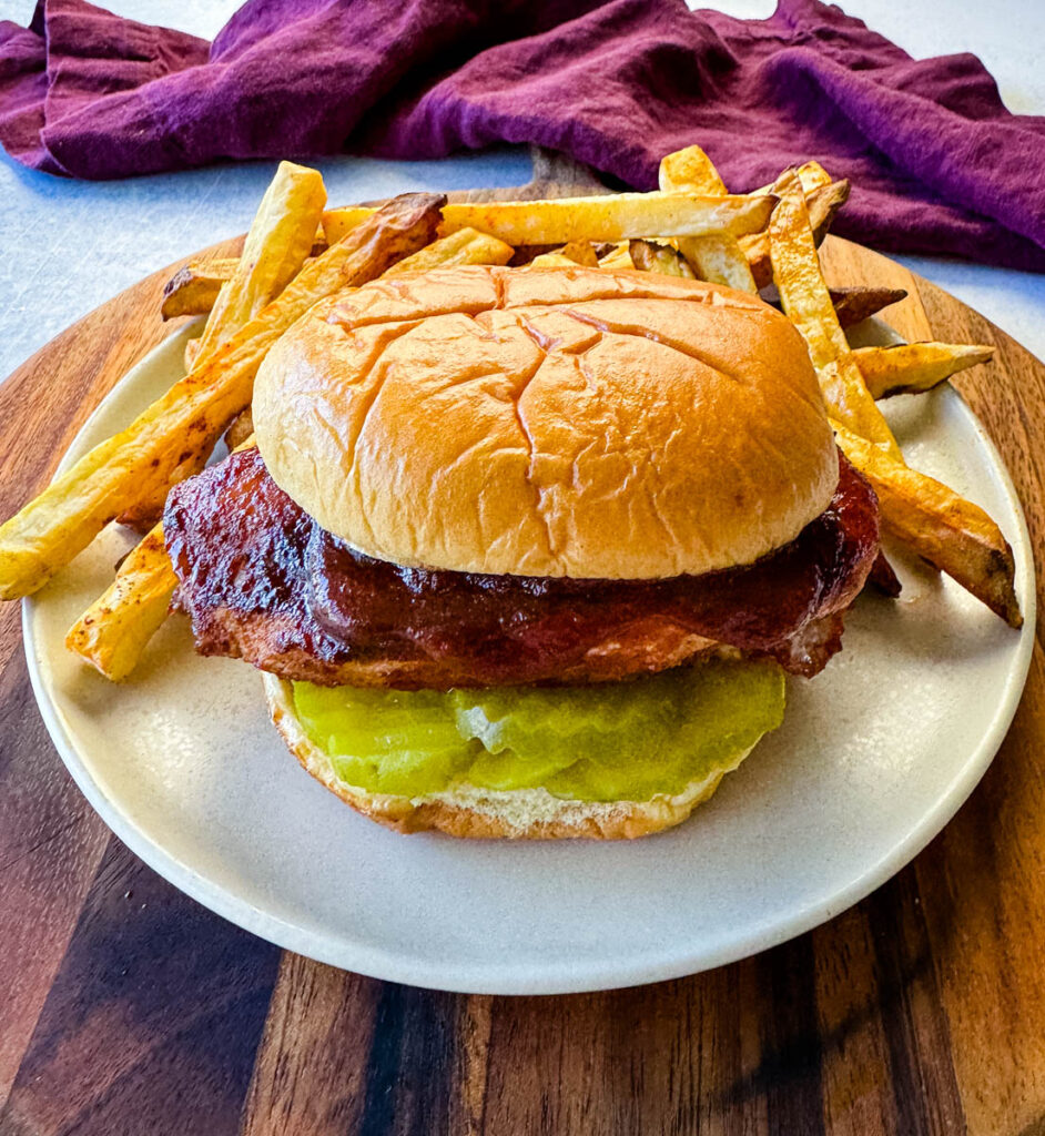 baked bbq chicken breast sandwich with fries on a platte