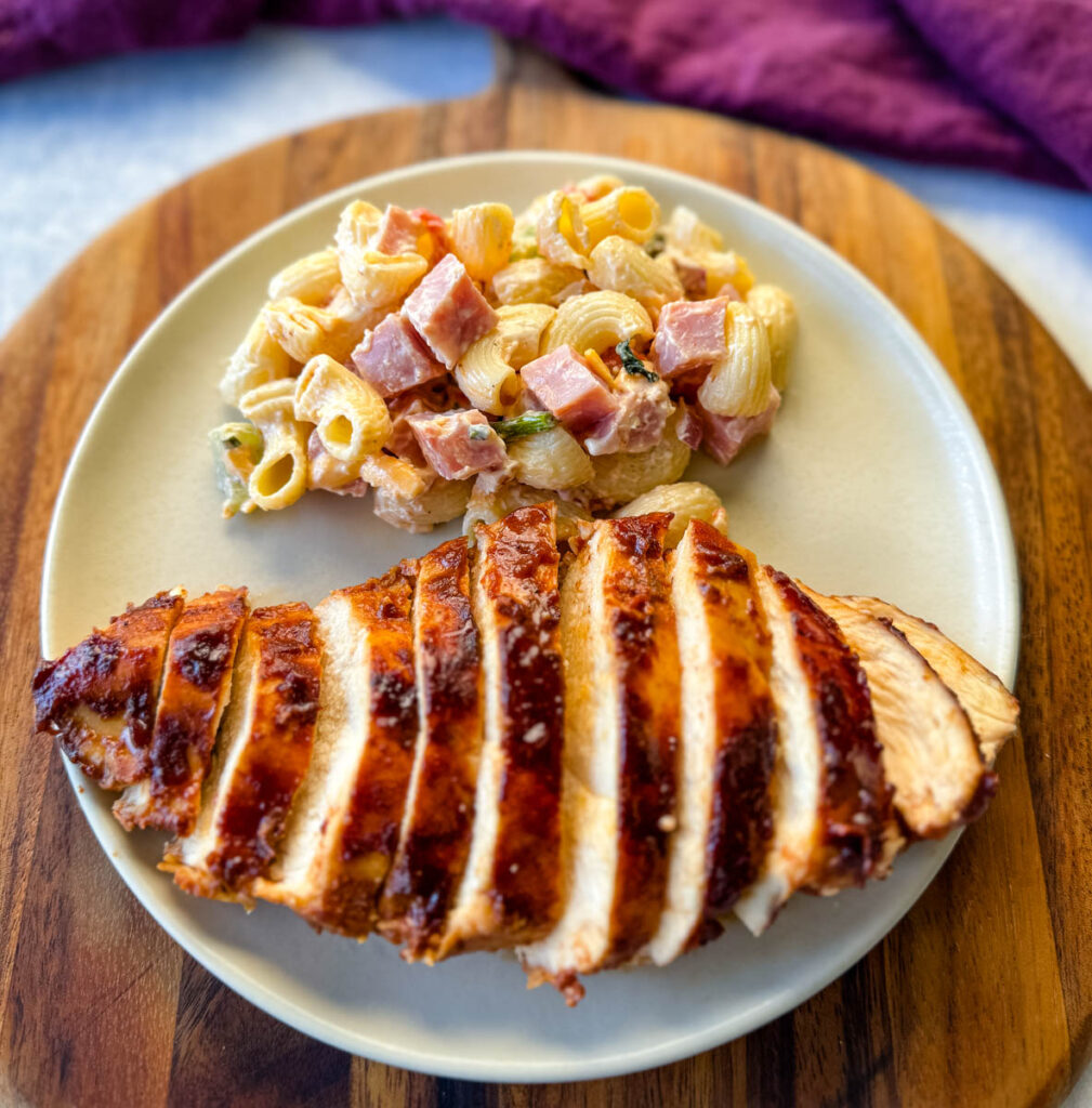 baked bbq chicken breast with pasta salad on a platte