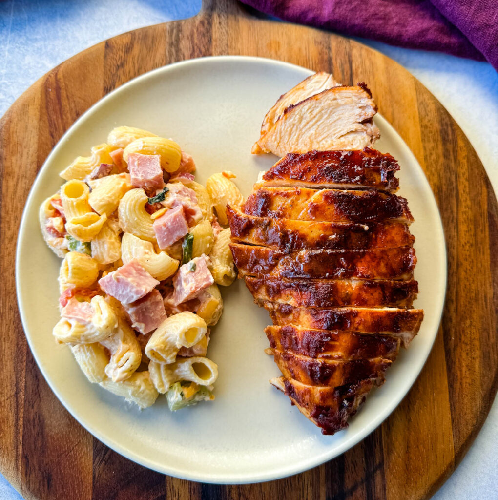baked bbq chicken breast with pasta salad on a platte