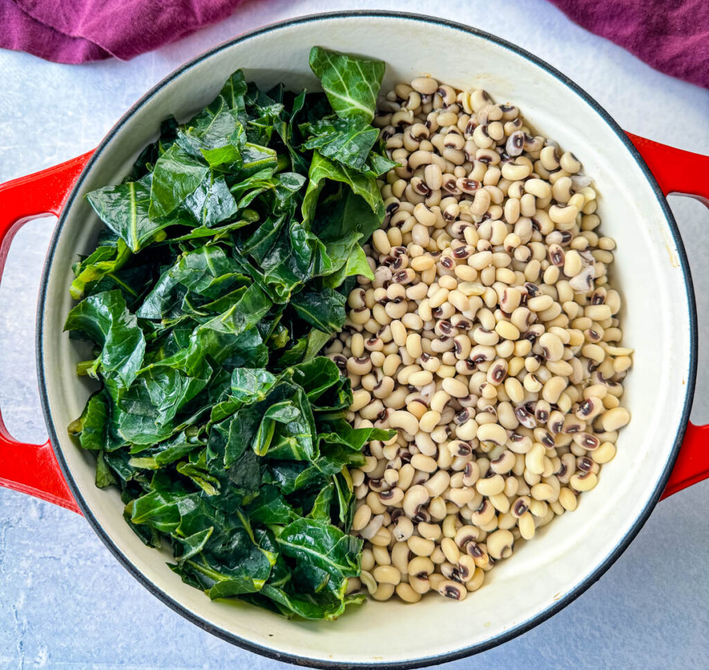 uncooked collard greens and black eyed peas in a red Dutch oven