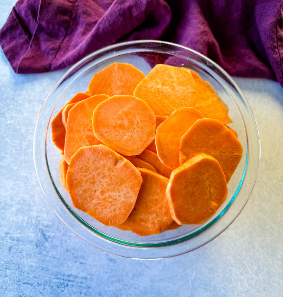 sweet potatoes sliced into rounds in a glass bowl