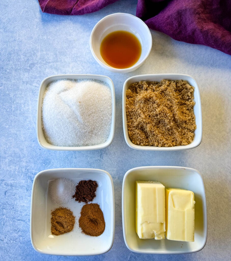 cinnamon, nutmeg, cloves, white sugar, brown sugar, butter, and vanilla in separate white bowls