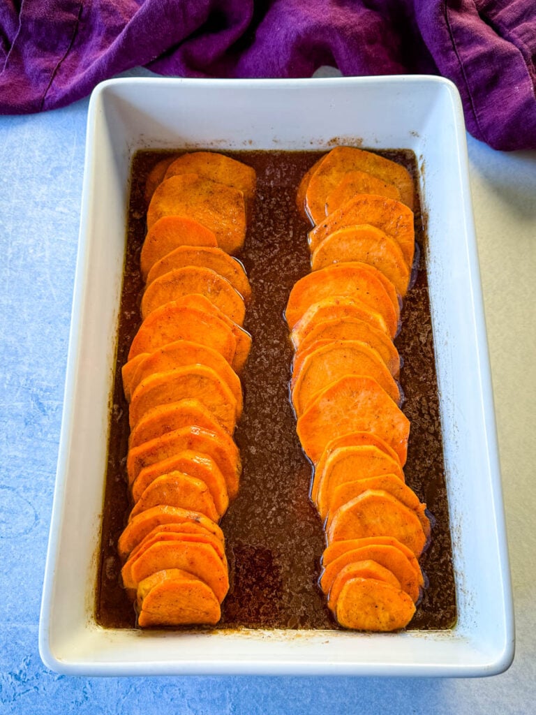 sliced sweet potatoes with brown sugar cinnamon glaze in a white baking dish