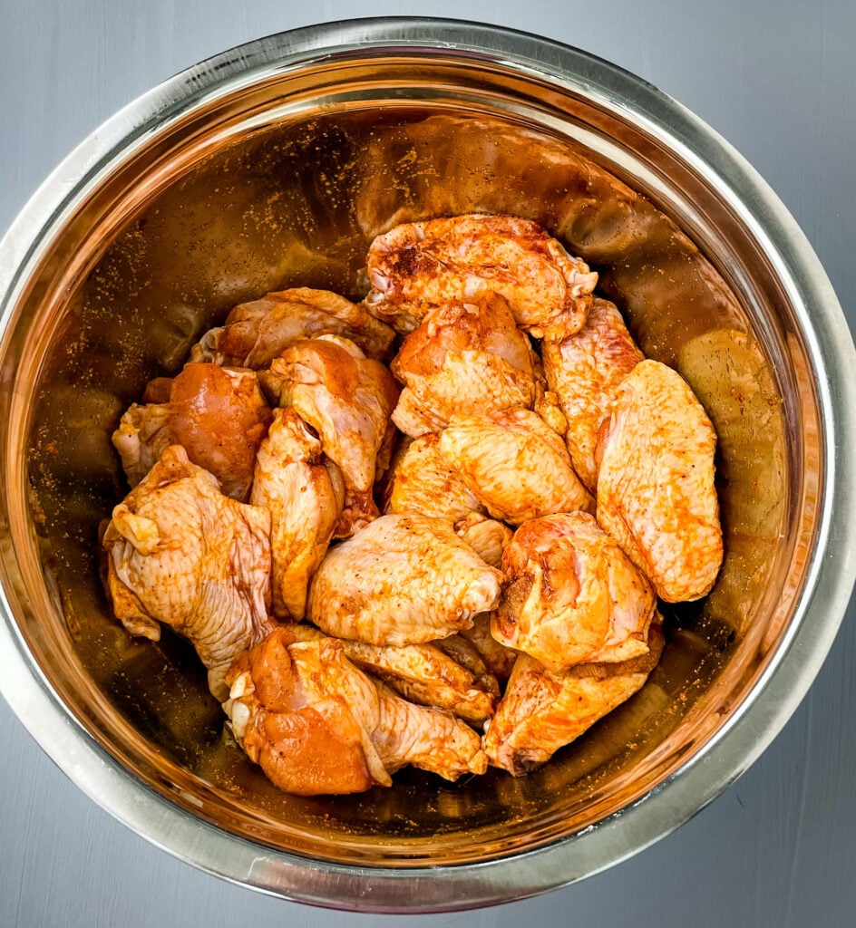 raw chicken wings seasoned with chicken seasoning marinade in a large bowl