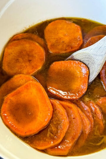 stovetop Southern soul food candied sweet potatoes yams in a Dutch oven with a wooden spoon