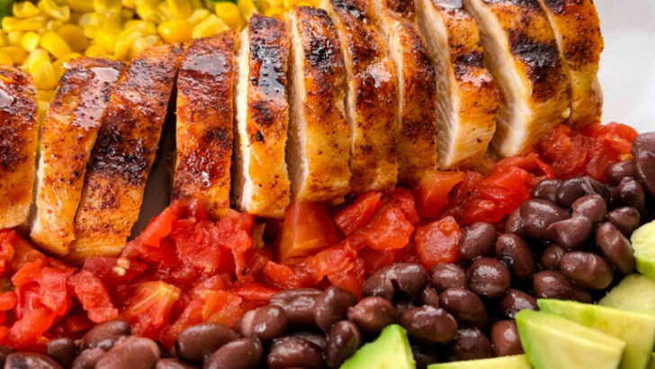 grilled chicken on a plate with vegetables and avocado