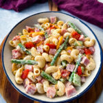 ham pasta salad with cheese, asparagus and tomatoes in a white bowl