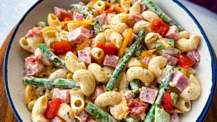 ham pasta salad with cheese, asparagus and tomatoes in a white bowl
