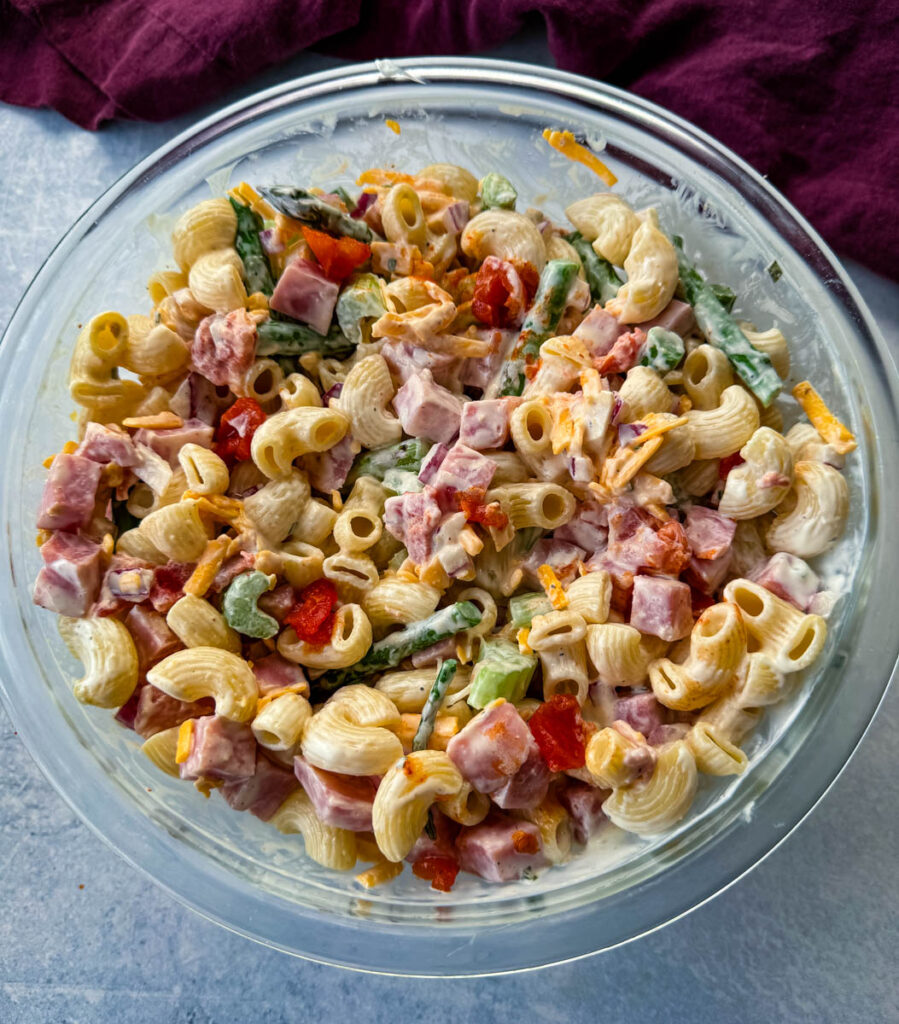 ham pasta salad with cheese, asparagus and tomatoes in a glass bowl