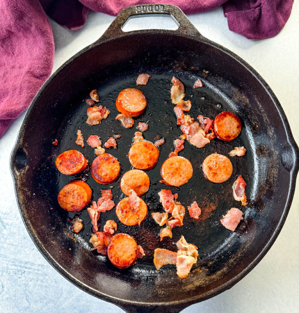 cooked sausage and bacon in a cast iron skillet