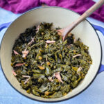 mixed greens, collard greens, turnip greens, mustard greens, and kale in a Dutch oven with a wooden spoon