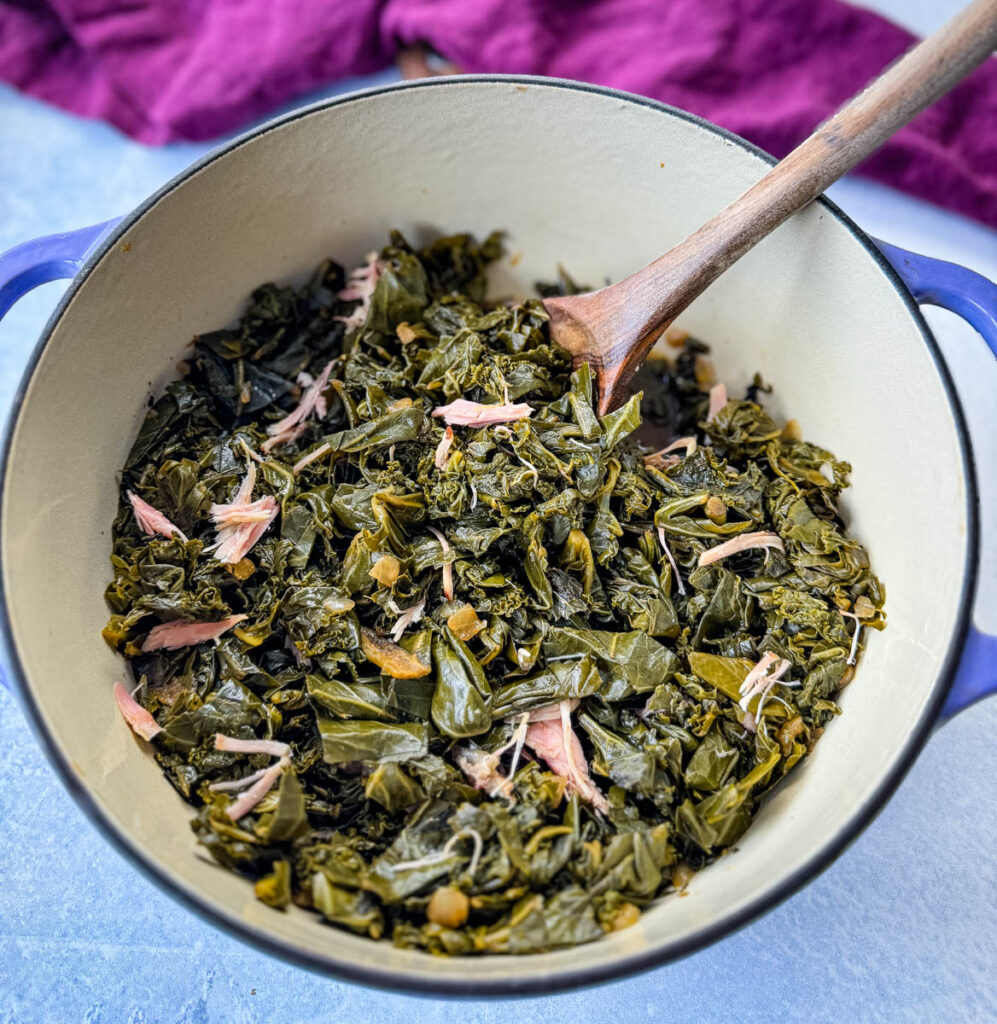 mixed greens, collard greens, turnip greens, mustard greens, and kale in a Dutch oven with a wooden spoon