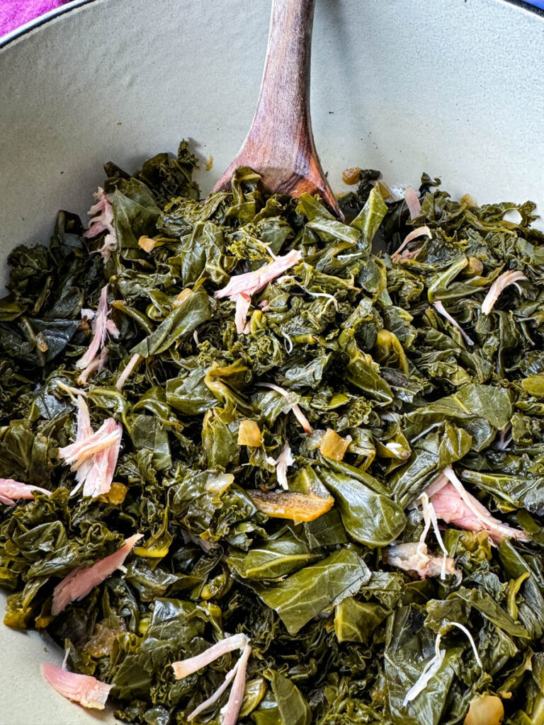 mixed greens, collard greens, turnip greens, mustard greens, and kale in a Dutch oven with a wooden spoon