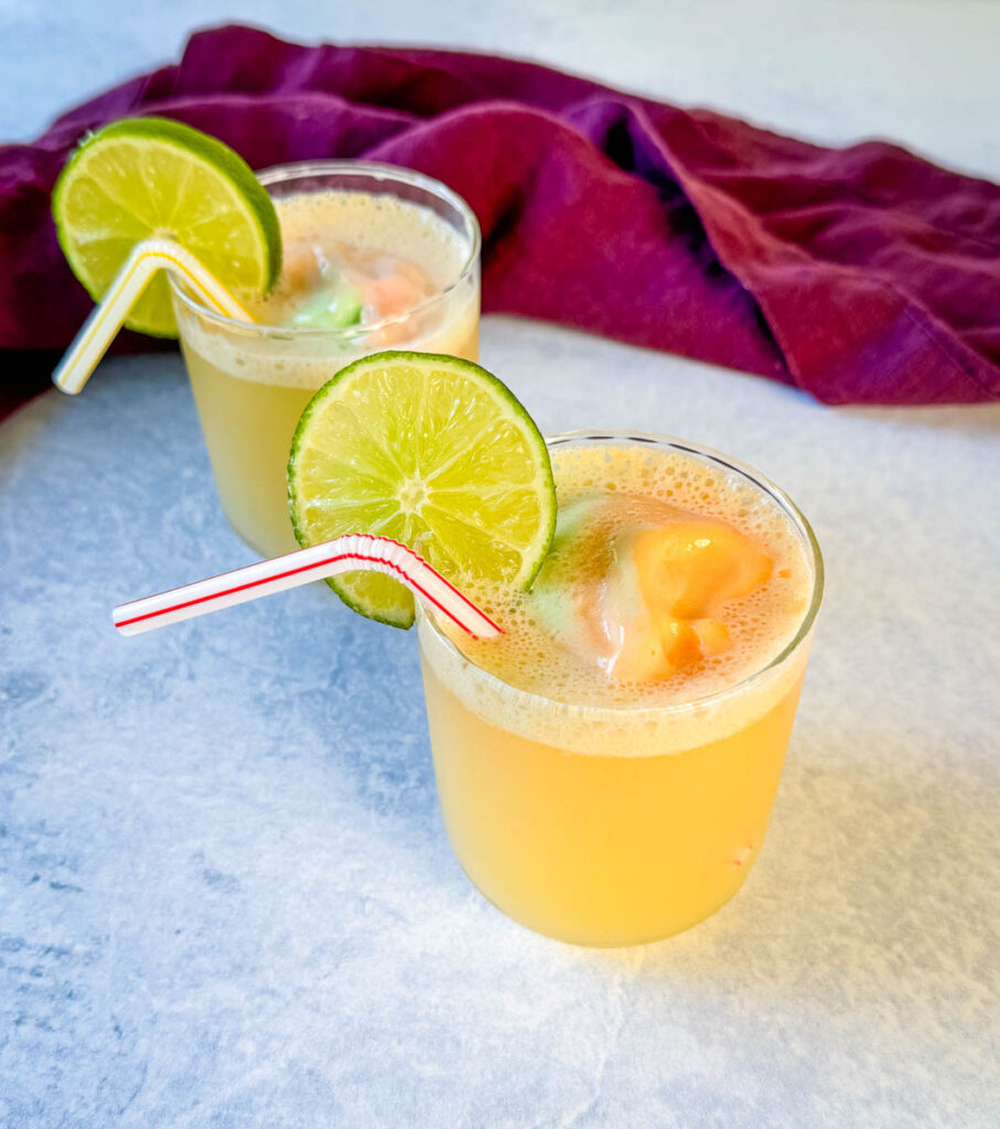 rainbow sherbet punch in a cup with a lime and straw