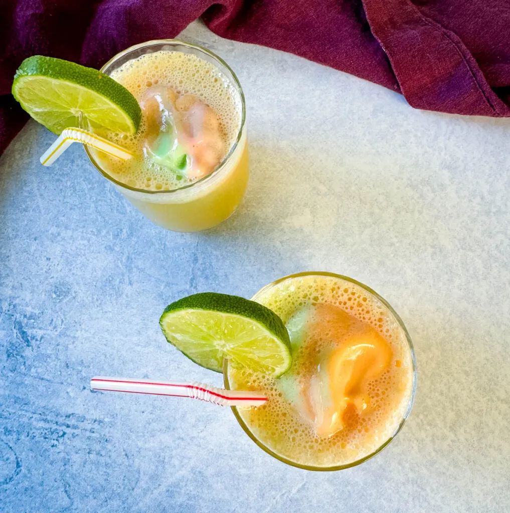 rainbow sherbet punch in a cup with a lime and straw