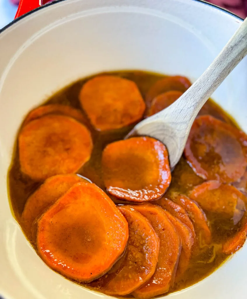 stovetop Southern soul food candied sweet potatoes yams in a Dutch oven with a wooden spoon