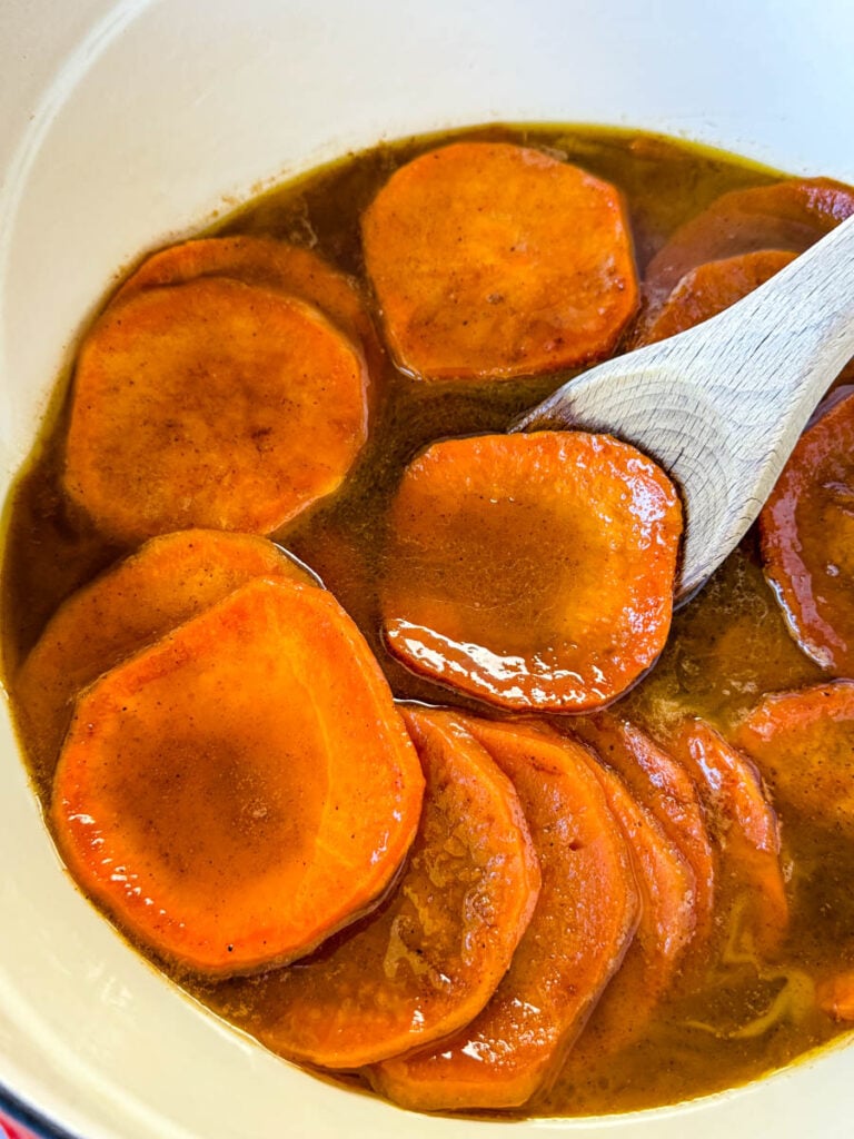 stovetop Southern soul food candied sweet potatoes yams in a Dutch oven with a wooden spoon