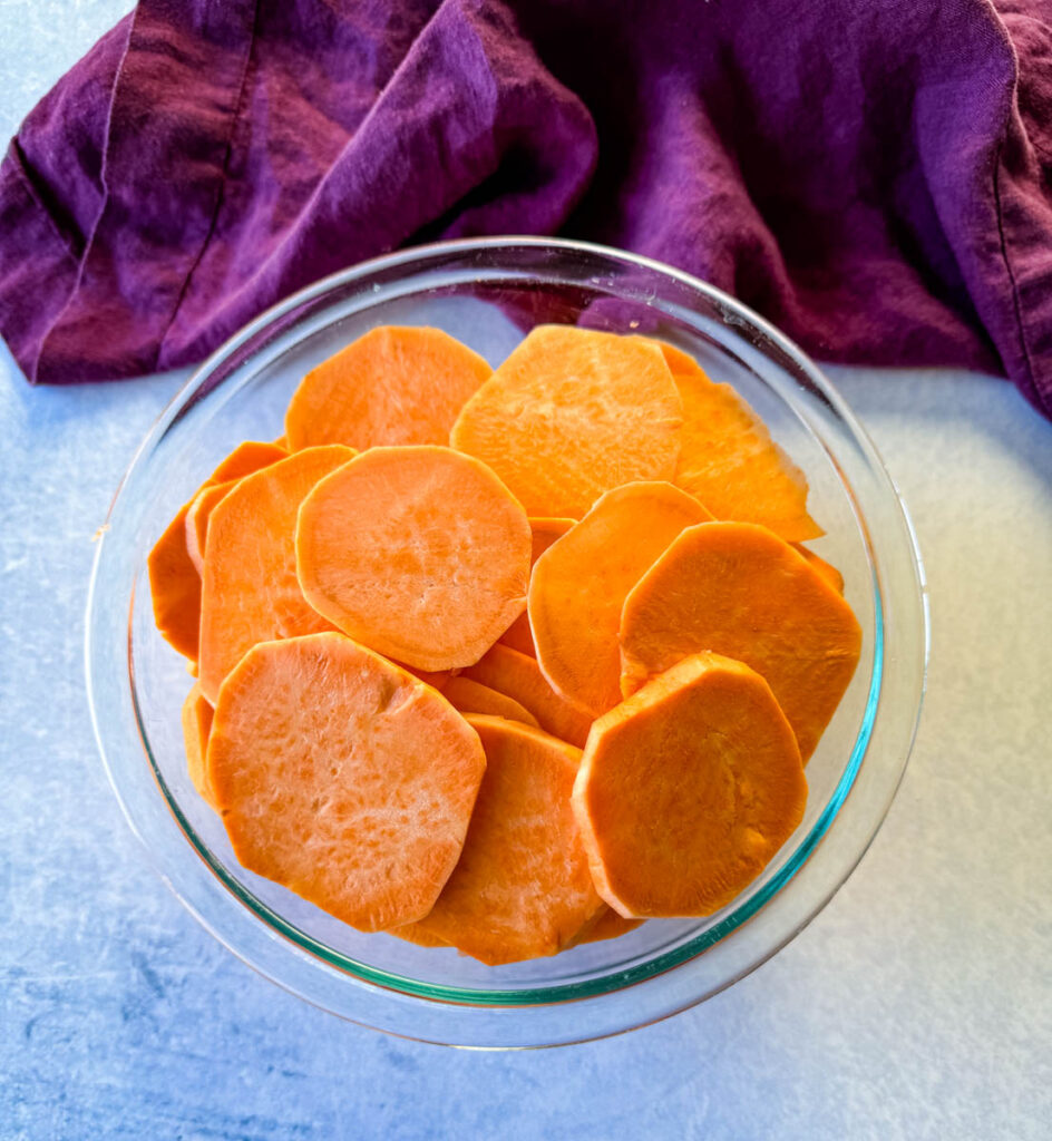sweet potatoes sliced into rounds in a glass bowl