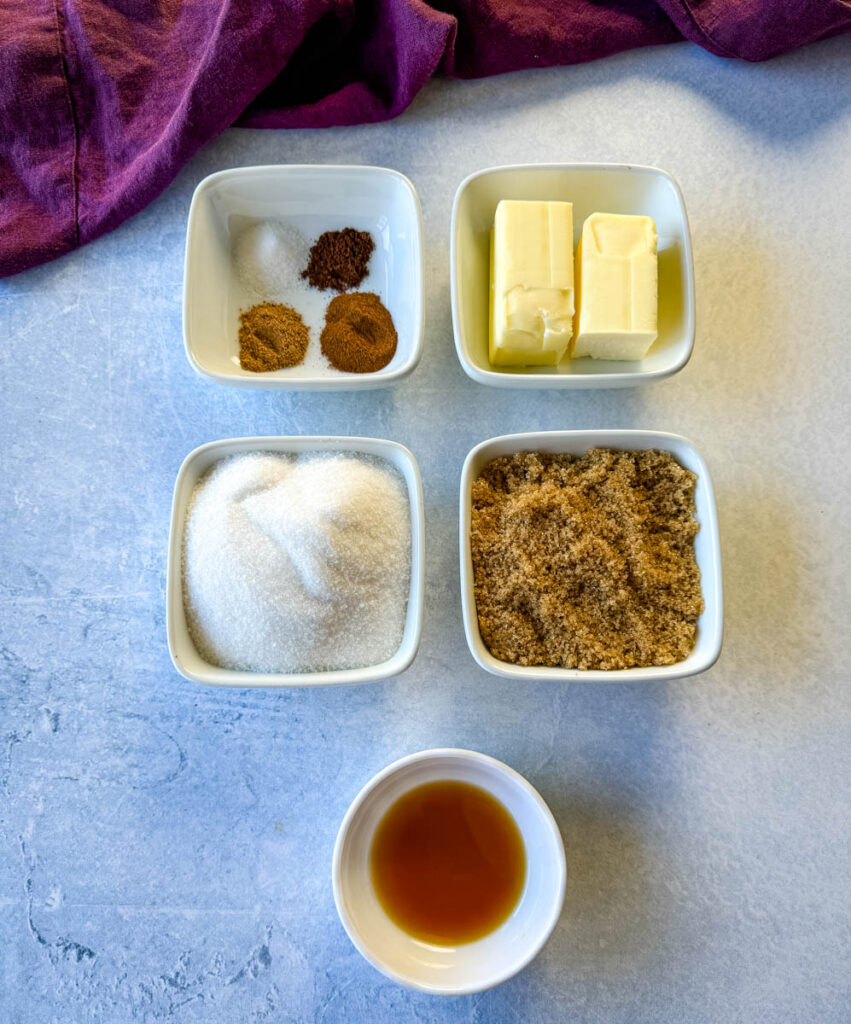 cinnamon, nutmeg, cloves, white sugar, brown sugar, butter, and vanilla in separate white bowls