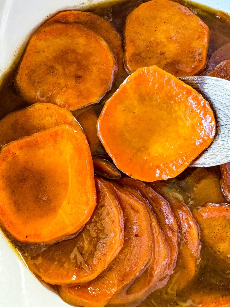 stovetop Southern soul food candied sweet potatoes yams in a Dutch oven with a wooden spoon