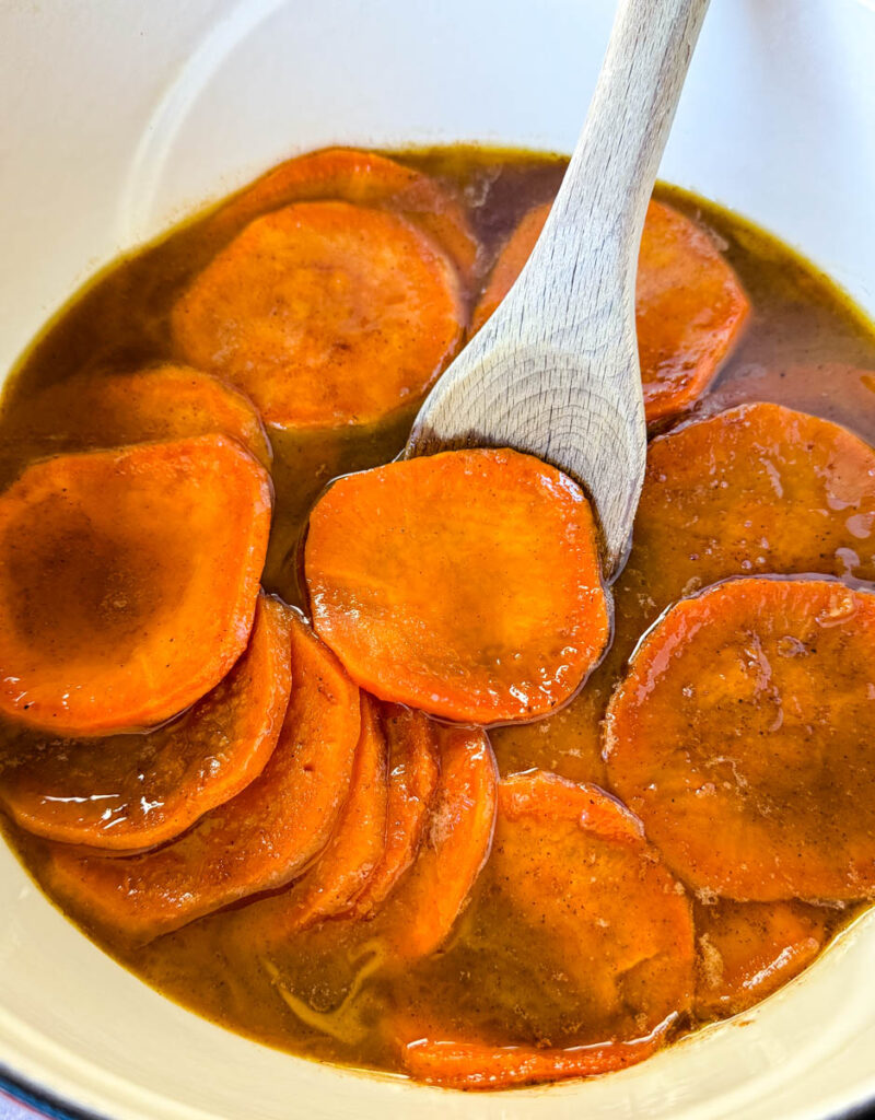 stovetop Southern soul food candied sweet potatoes yams in a Dutch oven with a wooden spoon